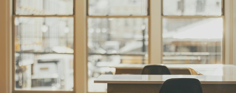 two white wooden tables near glass window
