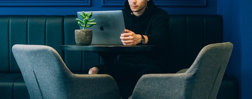man sitting on couch with looking at his MacBook on table