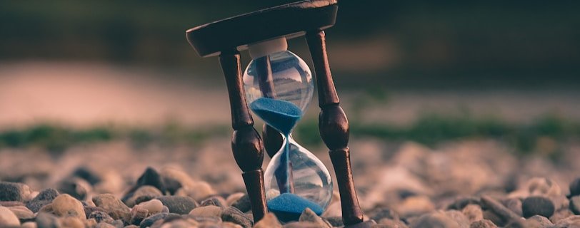 selective focus photo of brown and blue hourglass on stones