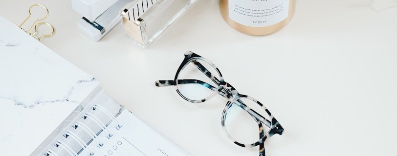 black framed eyeglasses beside spiral notebook