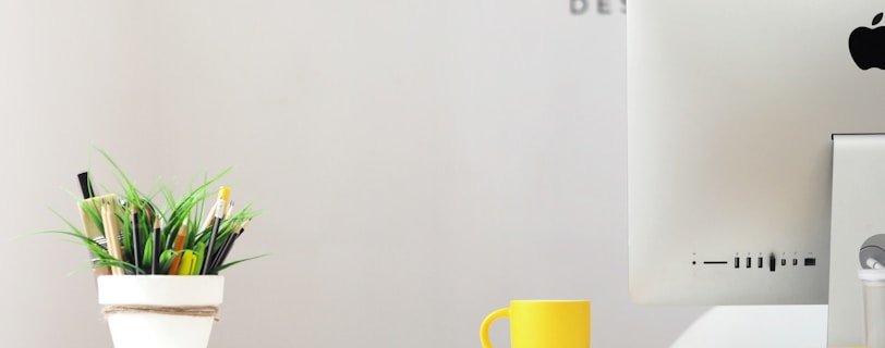 yellow ceramic mug beside gray aluminum iMac