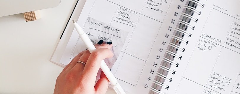 person holding notepad and pen flat lay photography