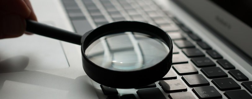 magnifying glass near gray laptop computer