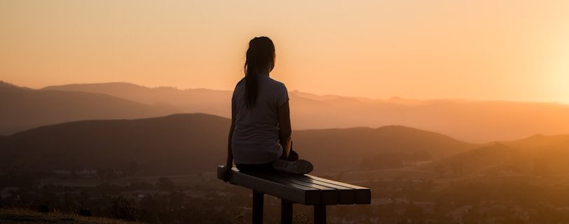 woman sitting on bench over viewing mountain