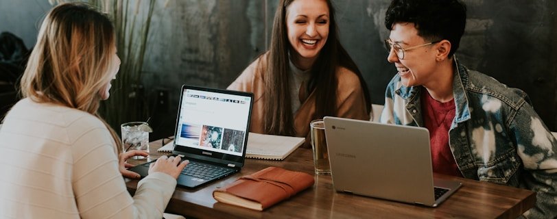 three people sitting in front of table laughing together