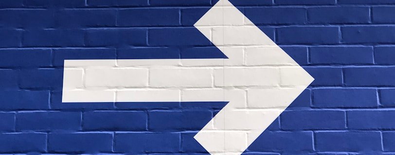 white arrow painted on brick wall