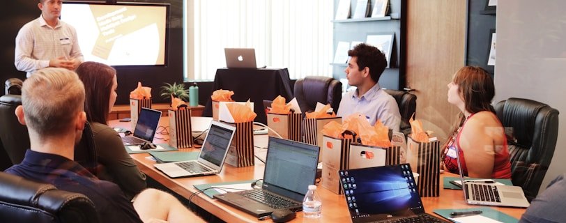 man standing in front of people sitting beside table with laptop computers