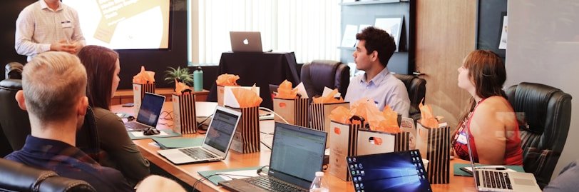 man standing in front of people sitting beside table with laptop computers