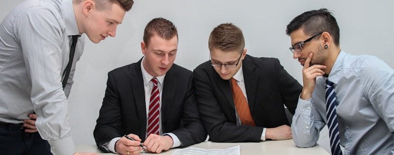 four men looking to the paper on table