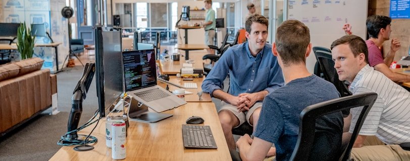 three men sitting on chair beside tables