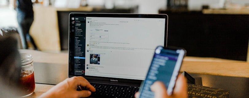 person using phone and laptop
