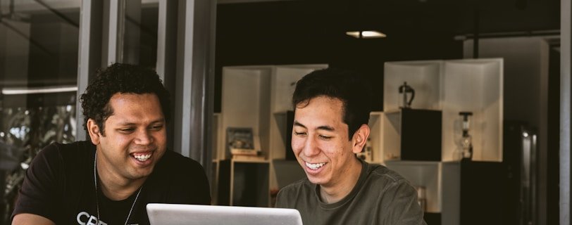 two smiling men looking at MacBook