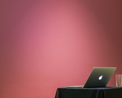 MacBook turned on beside clear drinking glass