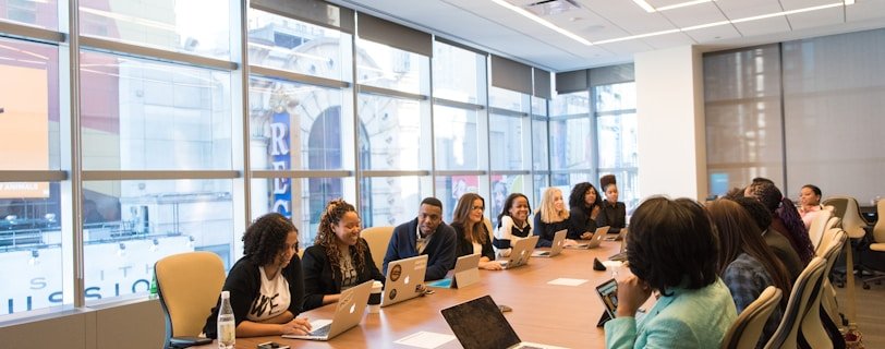 group of people sitting beside rectangular wooden table with laptops