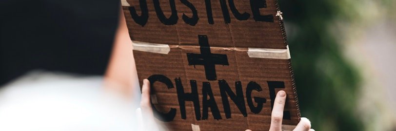 a person holding a sign that says we demand justice and change