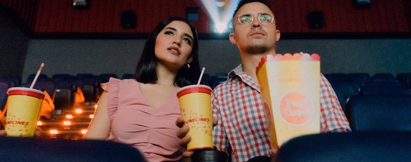 2 women sitting on blue leather chair holding white and red plastic cups