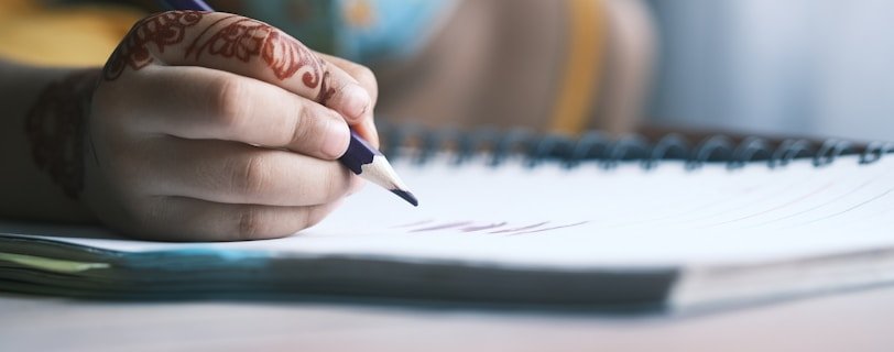 person writing on white notebook