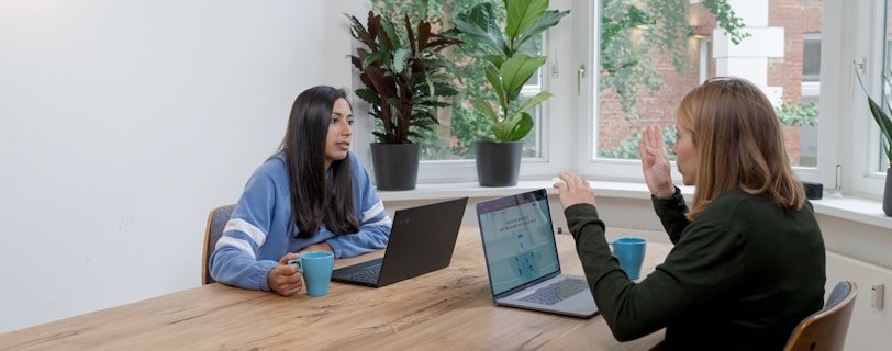 woman in blue long sleeve shirt sitting beside woman in black long sleeve shirt