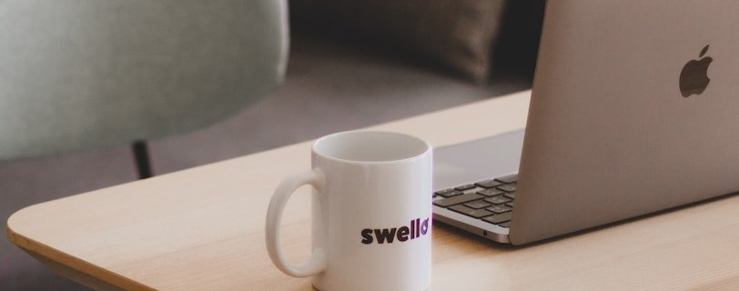 a coffee mug sitting on a table next to a laptop
