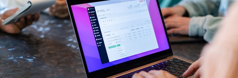 a group of people sitting at a table with laptops