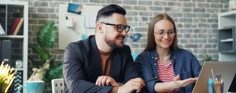 a man and a woman sitting at a table looking at a laptop