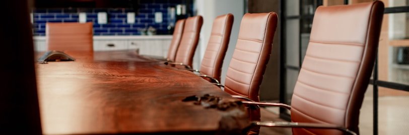 A conference room with a large wooden table and leather chairs