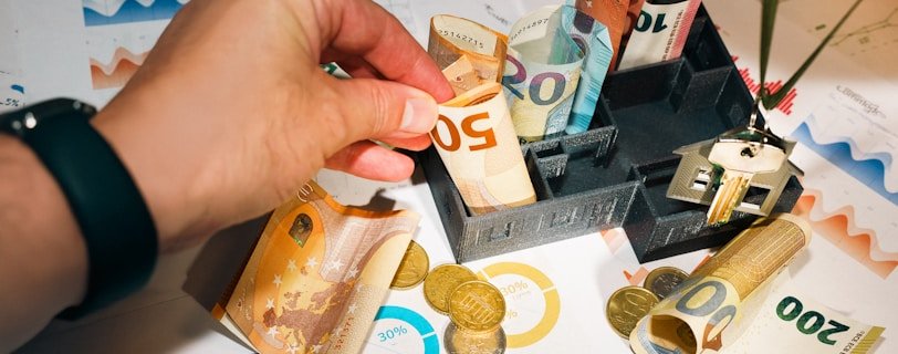 A person putting money into a miniature model house